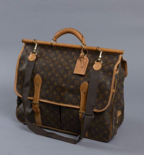 Louis VUITTON, Sac Chasse en toile Monogram, étiquette à bagage et poignée en cuir naturel, bandoulière ajustable en toile. D'un côté, une boucle de fermeture donnant sur une grande poche et un compartiment zippé, de l'autre double boucle de fermeture don