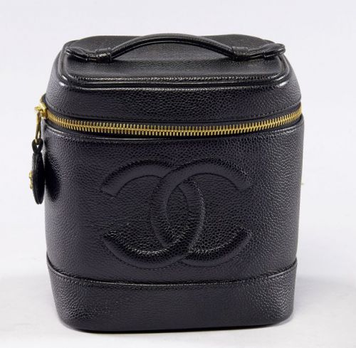 CHANEL, Vanity Bag PM en cuir noir grainé et siglé sur le devant, une anse de transport, intérieur en cuir souple à la couleur, fermeture zippée siglée. 17 x 15 cm. Griffures et patine d'usage sur le cuir, mais bel état général.