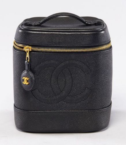 CHANEL, Vanity Bag PM en cuir noir grainé et siglé sur le devant, une anse de transport, intérieur en cuir souple à la couleur, fermeture zippée siglée. 17 x 15 cm. Griffures et patine d'usage sur le cuir, sinon bel état général.