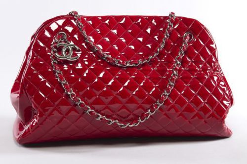 CHANEL, Grand cabas en cuir verni matelassé rouge. Deux chaînes en métal blanc entrelacées de cuir à la couleur. Grand sigle CC en métal. Fermeture par bouton aimanté. Intérieur en tissu rouge, trois compartiments dont un zippé. Trois poches dont une zipp