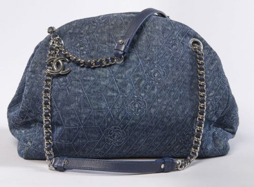 CHANEL, Sac shopping en denim bleu surpiqué de camélias à la couleur, une anse chaîne en métal de couleur argenté entrelacée de cuir bleu, CC en pendeloque, trois compartiments dont un zippé et trois poches dont une zippée. 28 x 32 cm. Carte d'authenticit