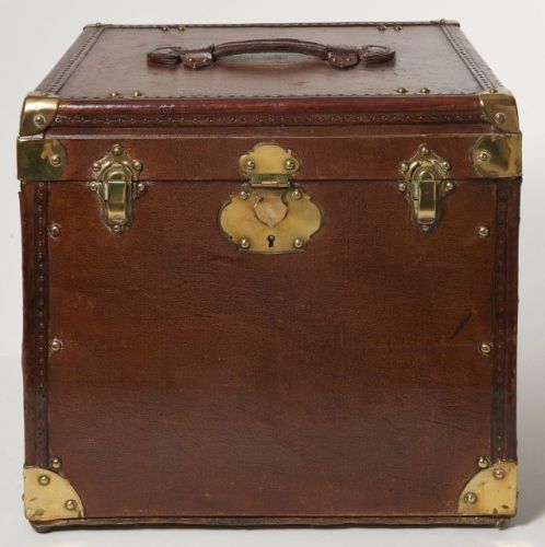 ANONYME, Jolie petite malle cubique en toile enduite, bordures lozinées, garnitures en laiton. Une poignée de portage en cuir à la couleur sur le dessus. Intérieur en velours vert avec sangles de maintien. 36,5 x 41 x 37 cm. Belle patine.