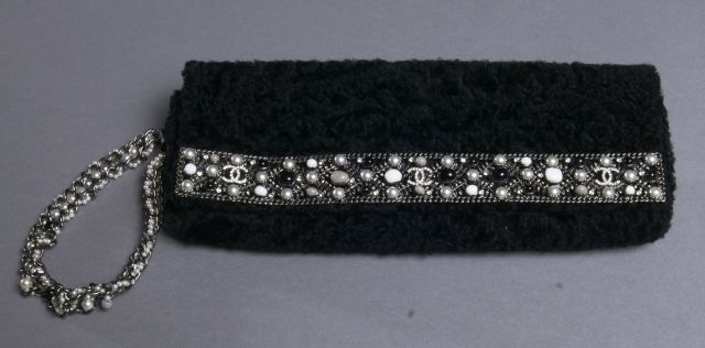 CHANEL Collection Haute Couture! Magnifique pochette noire en astrakan, ornée d'un bandeau en métal ajouré entièrement serti de strass et perles d'imitation blanches et noires et de 3 sigles strassés, anse dragonne en chaîne sertie de perles nacrées, inté