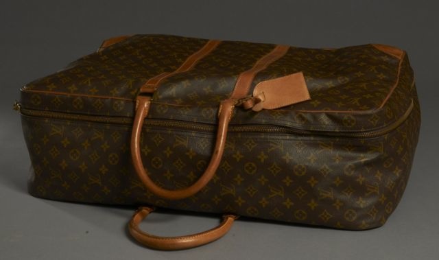 Louis VUITTON Valise souple en toile Monogram et cuir naturel, une grande poche à l'intérieur, porte étiquette. Petites usures aux coins, cuir légèrement taché mais trés bel état général.