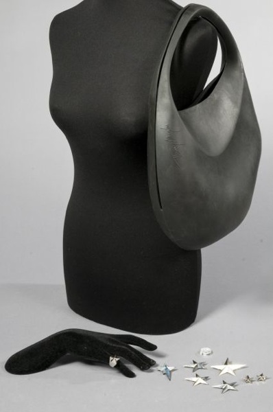 Thierry MUGLER, CHANEL SAC en caoutchouc noir, double poignée, fermeture boules (petite patine d'usage). Nous y joignons CINQ BROCHES, DEUX PIN'S et une BAGUE étoilée en métal argenté ainsi qu'un bouton en verre transparent blanc siglé (petit éclat)