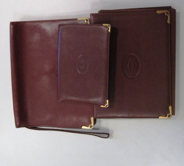 MUST de CARTIER LOT en cuir bordeaux comprenant un REPERTOIRE, un PORTEFEUILLE et une POCHETTE munie de sa dragonne (mini 