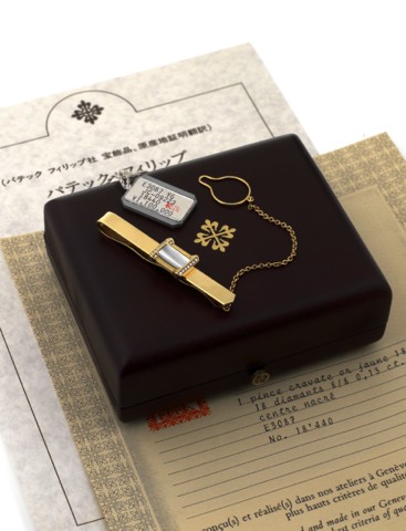 Patek Philippe, Geneve, Tie Clip, No. 18440.Ref. E3087..An 18K yellow gold, diamond and mother of pearl money clip.with chain. Accompanied by fitted box, Certificate of Origin.and hang tag..To be sold without reserve
