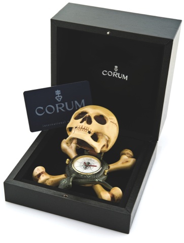 CORUM JOLLY ROGER ALARM CLOCK.Corum, Jolly Roger, No. 82331, Ref. 3.101.25. Made in a.limited edition, sold in October 2005..Painted metal quartz form clock in the shape of a skull.atop a snake and crossbones, with concealed dial and.alarm. Accompanied by