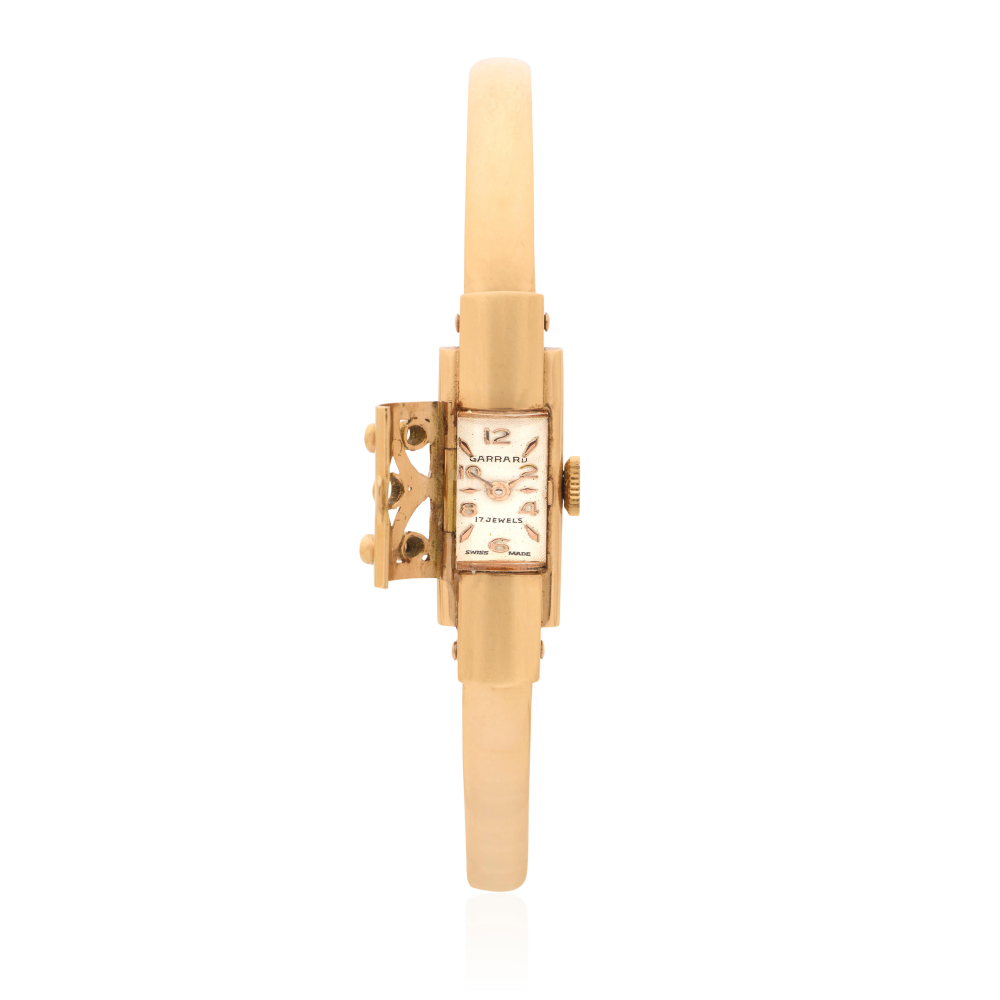 Garrard. A lady's 18K gold manual wind bangle watch with concealed dial