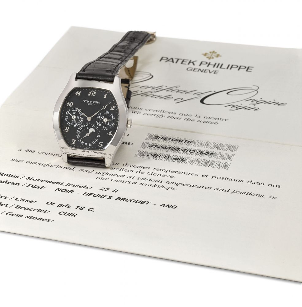 Patek Philippe. An extremely fine and very rare 18K white gold automatic tonneau-shaped perpetual calendar wristwatch with moon phases, black dial, Breguet numerals and original certificate