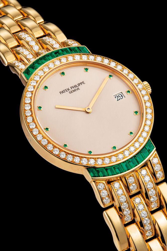 PATEK PHILIPPE. AN 18K GOLD, DIAMOND AND EMERALD-SET BRACELET WATCH WITH DATE