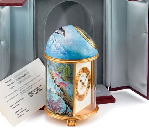 Patek Philippe. A very fine and unique gilt brass solar-powered table clock with cloisonne enamel Voyage aux Iles by Michele Mauris, original certificate and box
