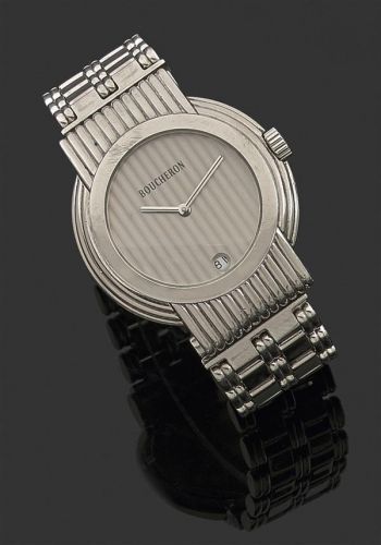 BOUCHERON. SOLIS. Montre bracelet en acier avec boîtier rond godronné et attaches striées. Cadran argenté avec guichet dateur à 6h. Mouvement quartz. Bracelet acier avec attaches coulissantes, signé Boucheron.. Signée et numérotée AG232222.. Diam. 34 mm. 